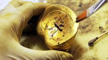 Очистка золотого слитка в форме лошадиного копыта, найденного в гробнице Хайхуньхоу. Фото: Xinhua